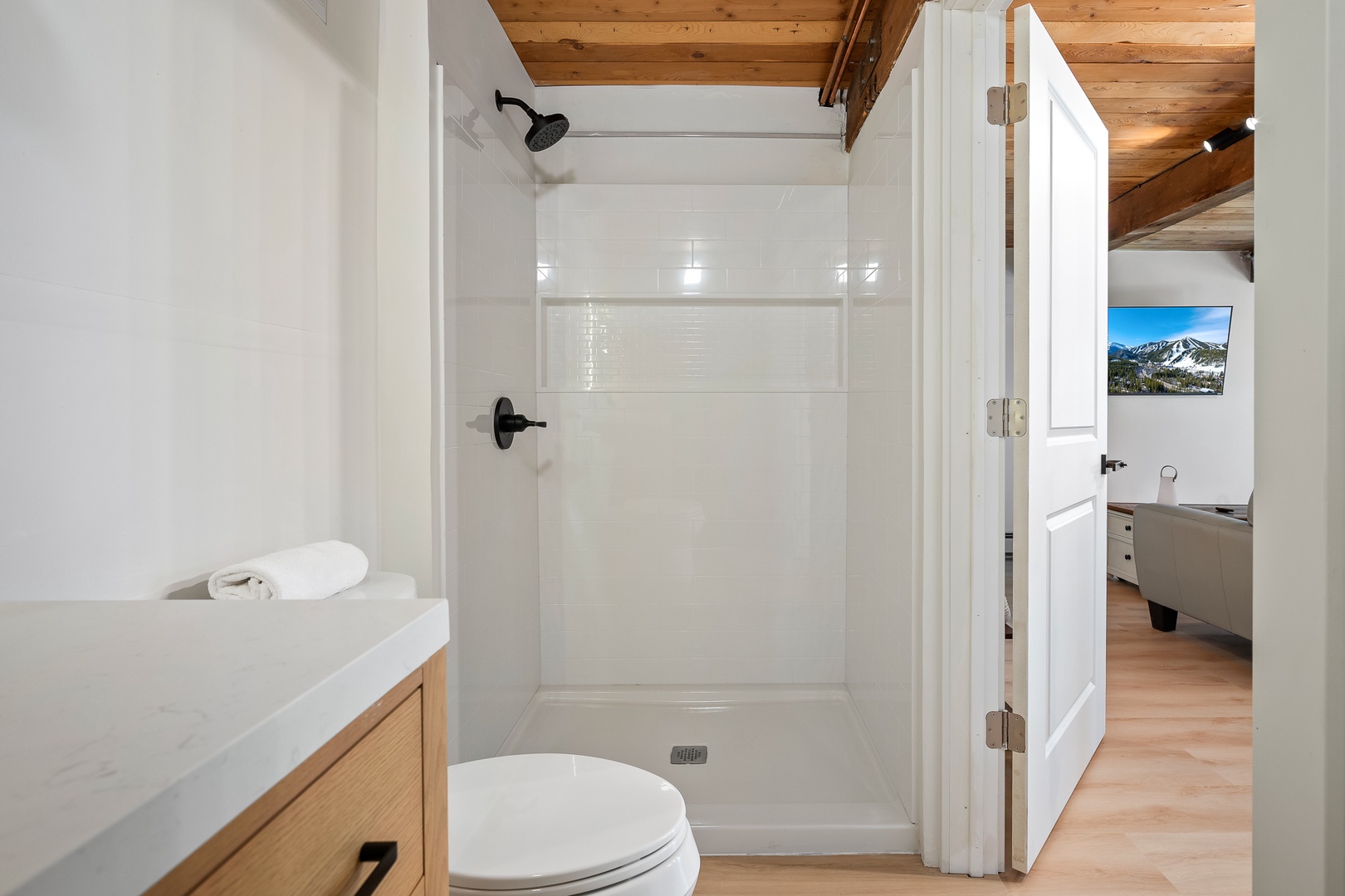 Freshen up in your modern bathroom, complete with a sparkling walk-in shower, wooden accents above, and thoughtful touches like fresh towels waiting for you.