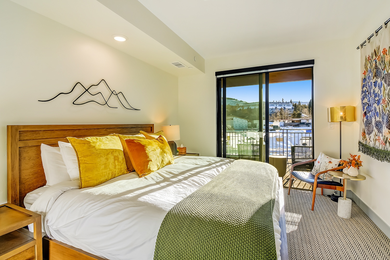 Wake up in this stylish bedroom where vibrant pillows and mountain art create warmth, while your private balcony overlooks scenic views.