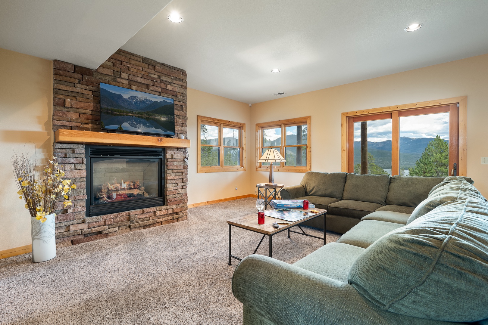 Settle into your spacious living room where mountain-framed windows flood the space with natural light. Gather around the cozy stone fireplace and sink into plush seating while taking in stunning vistas.