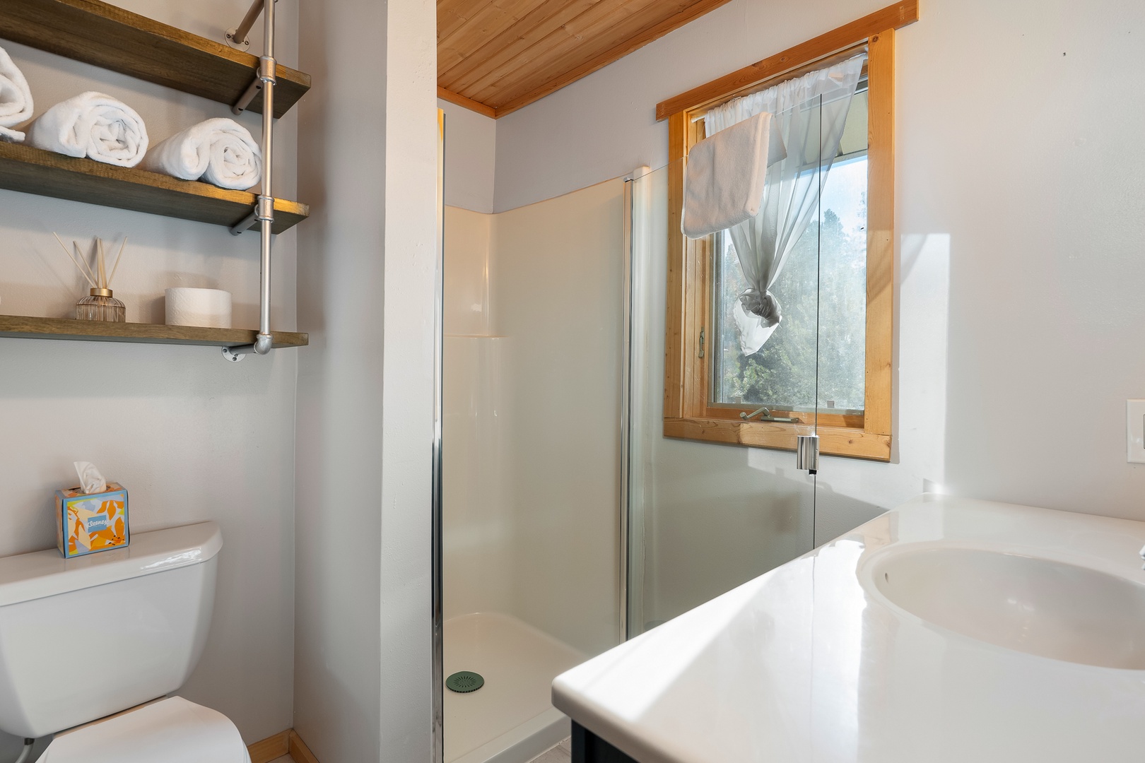 Unwind in your spa-like bathroom with gleaming surfaces, fluffy towels, and natural light streaming through charming wood-framed windows.