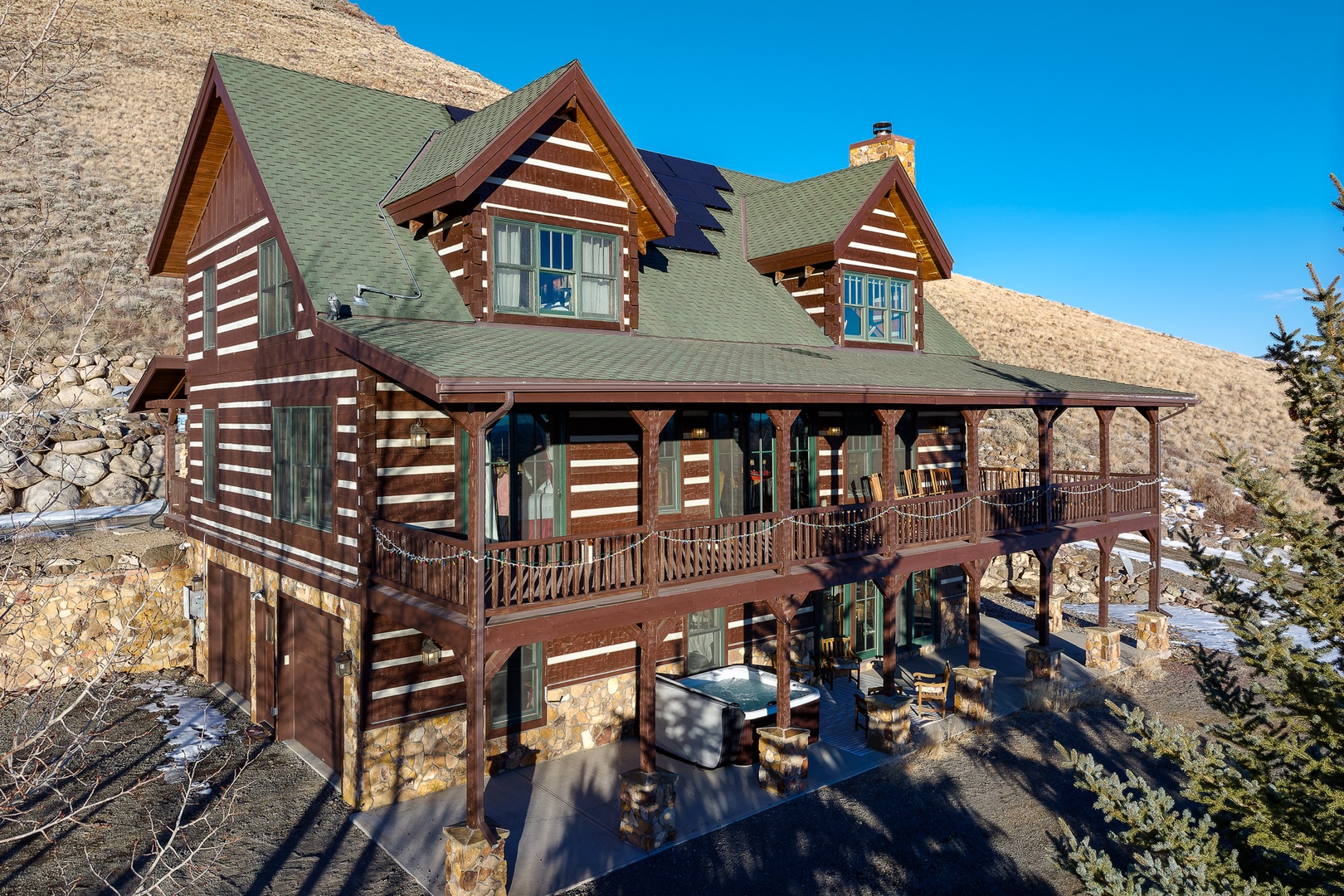 Beautiful log cabin nestled in rugged mountain terrain, featuring wraparound decks and stunning alpine views.