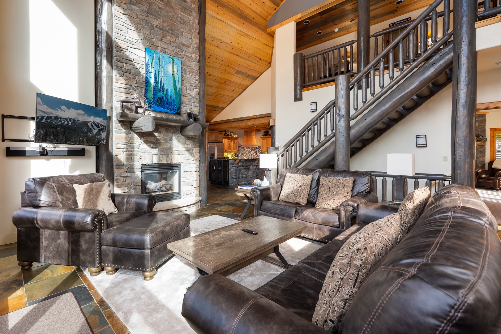 Unwind in your spacious living room with soaring ceilings, stone fireplace, and luxurious leather seating perfect for mountain evenings.