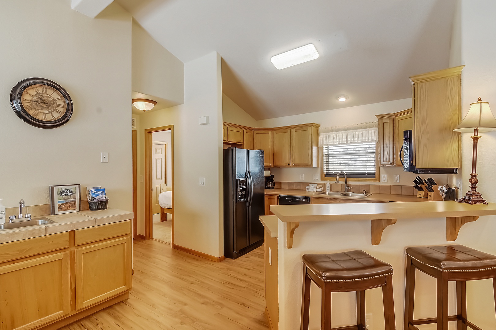 Your fully equipped kitchen welcomes you with warm wood cabinetry, granite countertops, and a cozy breakfast bar for morning coffee.