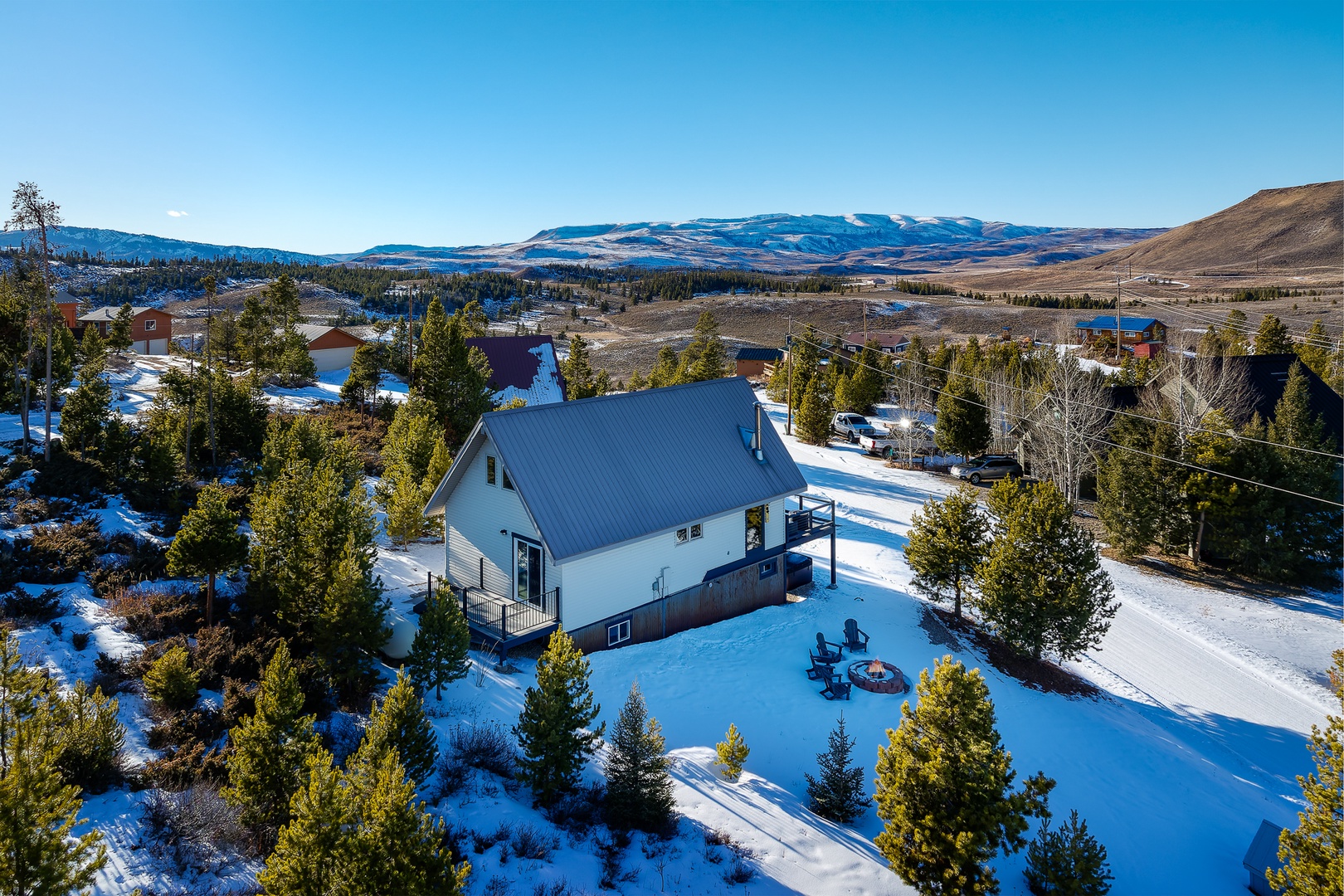 Winter mountain property surrounded by pristine snow and evergreen trees, offering scenic views of rolling hills.