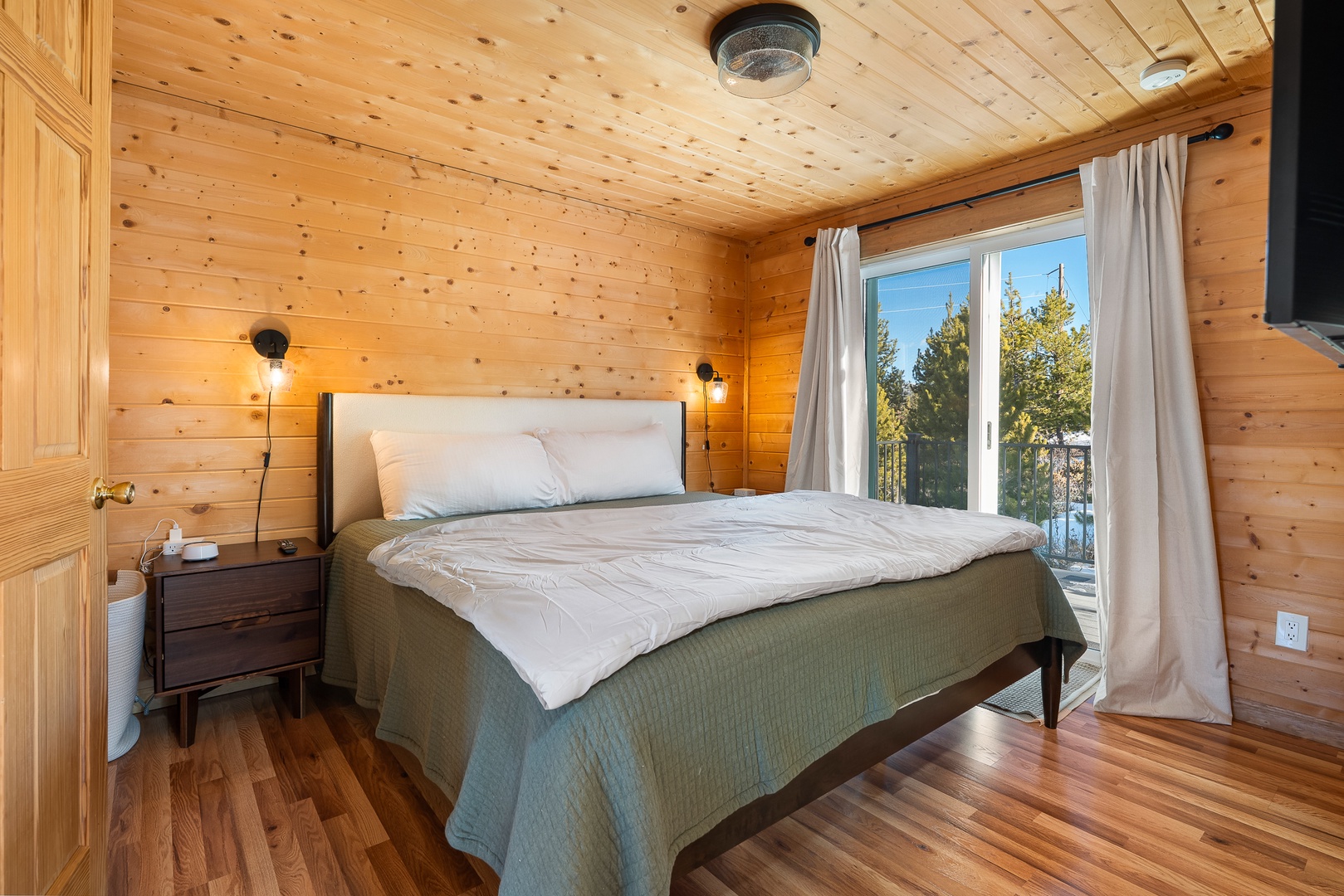 Drift off peacefully in your cozy wooden haven, where warm pine walls embrace you and natural light streams through your private balcony door.