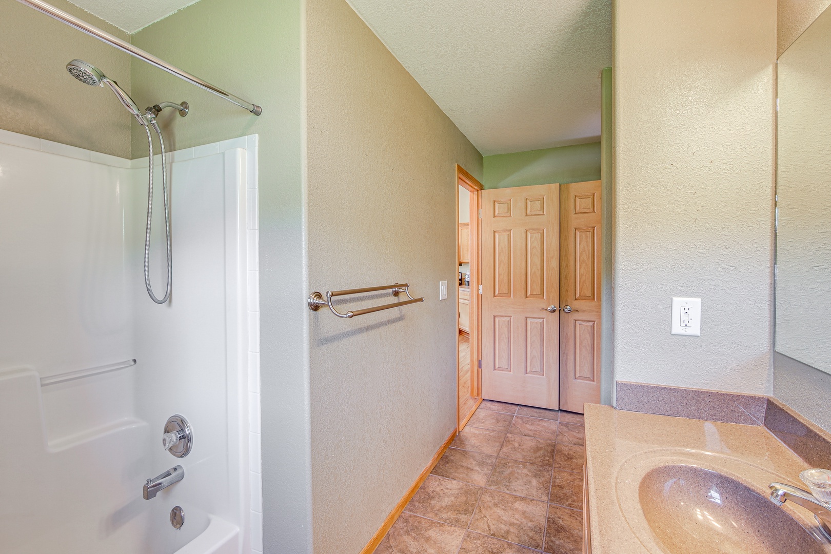 Refresh in your private bathroom featuring a shower-tub combo with safety bars and warm neutral tones throughout.