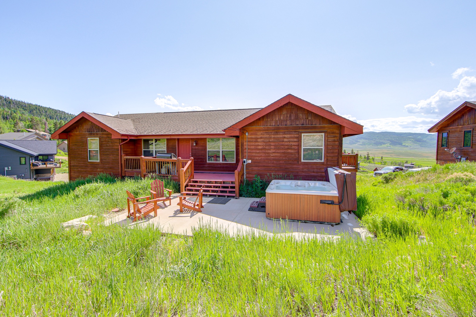 Charming mountain cabin featuring a private hot tub and outdoor seating area surrounded by expansive natural meadows.