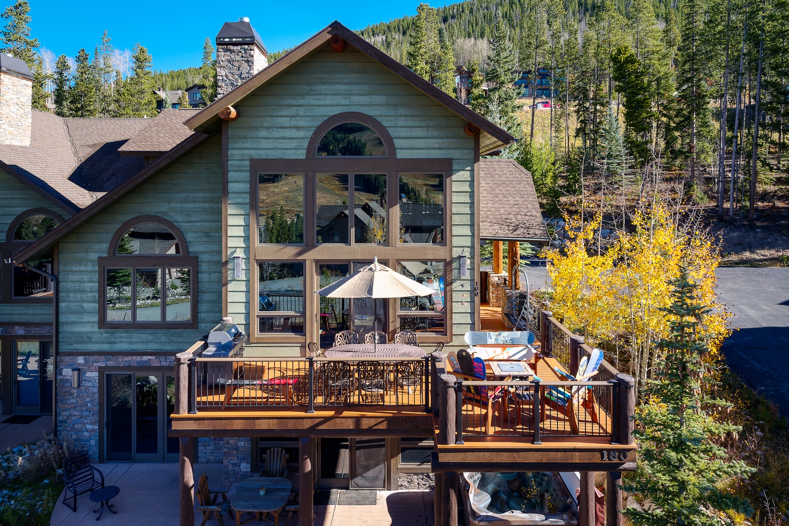 Mountain retreat featuring multi-level decks and forested hillside setting with autumn foliage and panoramic views.