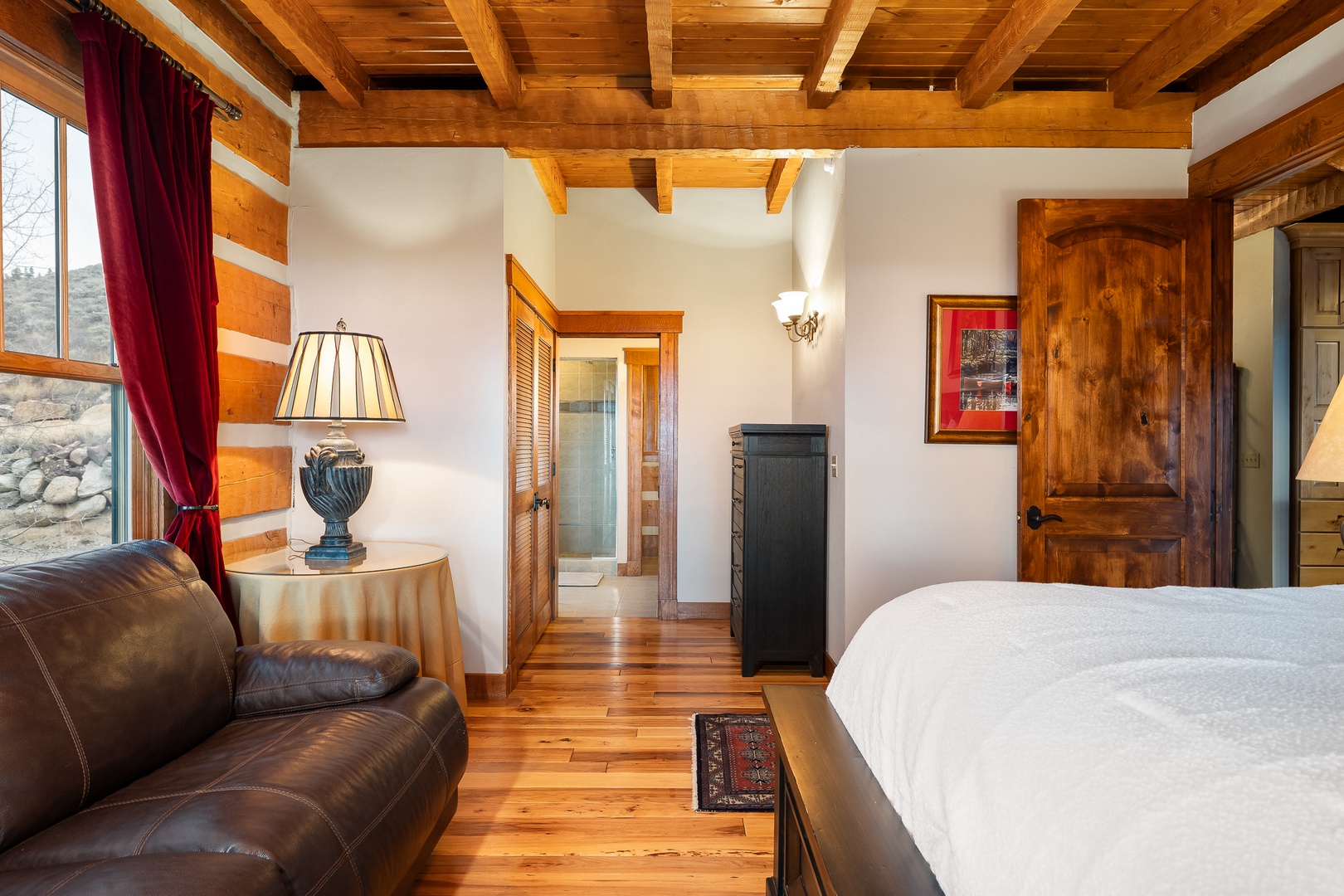 Unwind in this rustic-chic bedroom where exposed beams and rich wood create a cozy mountain retreat for your perfect getaway.