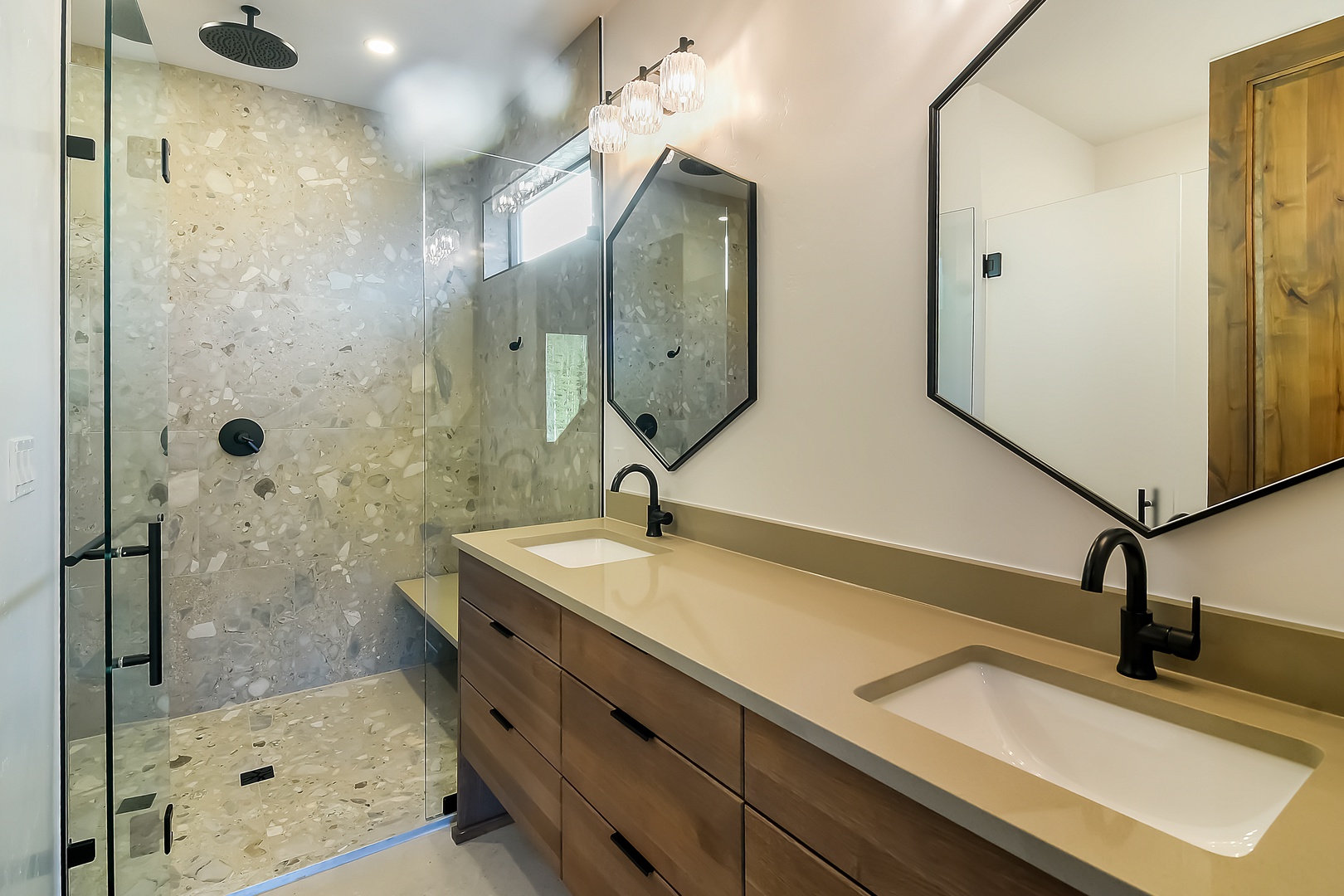 Unwind in your sleek bathroom featuring a spacious walk-in shower, elegant pendant lighting, and modern dual vanities for your comfort.