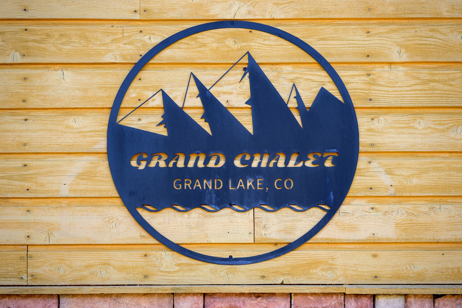 The Grand Chalet welcomes you to Grand Lake, Colorado, nestled among mountain peaks and alpine charm. This distinctive logo marks your arrival to a cozy mountain getaway.