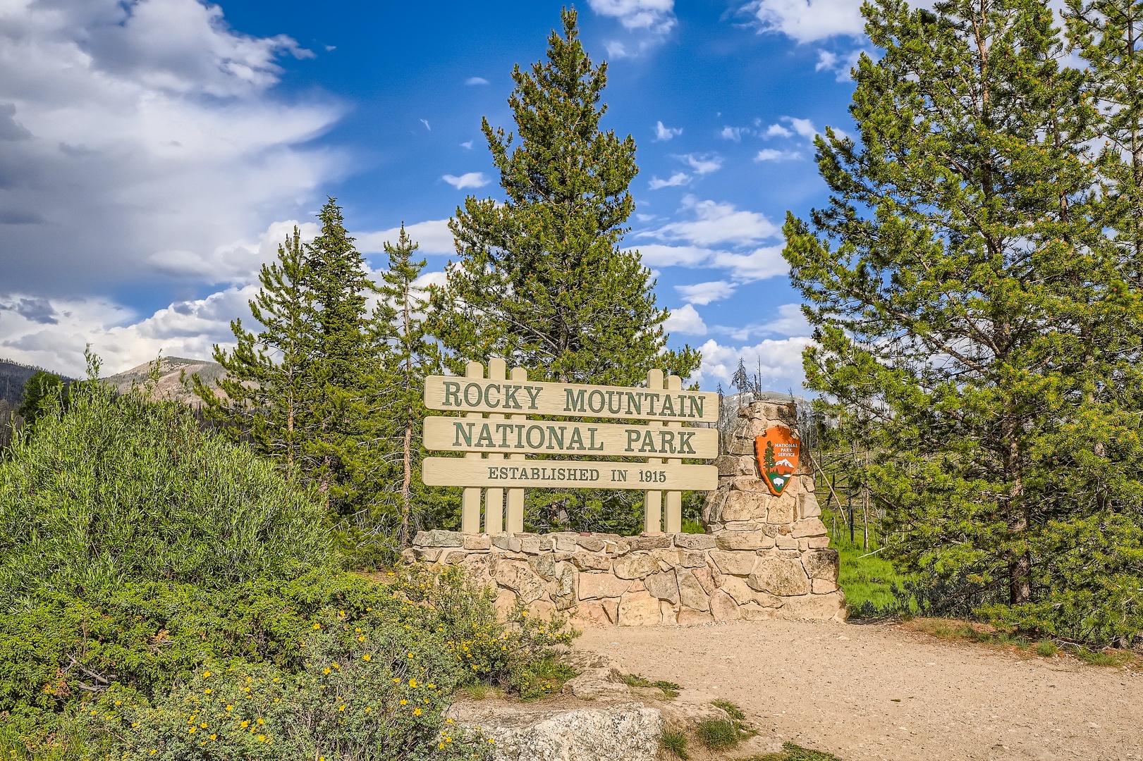 Rocky Mountain National Park entrance marker, a notable landmark near the property, set among evergreen pines and mountain scenery.