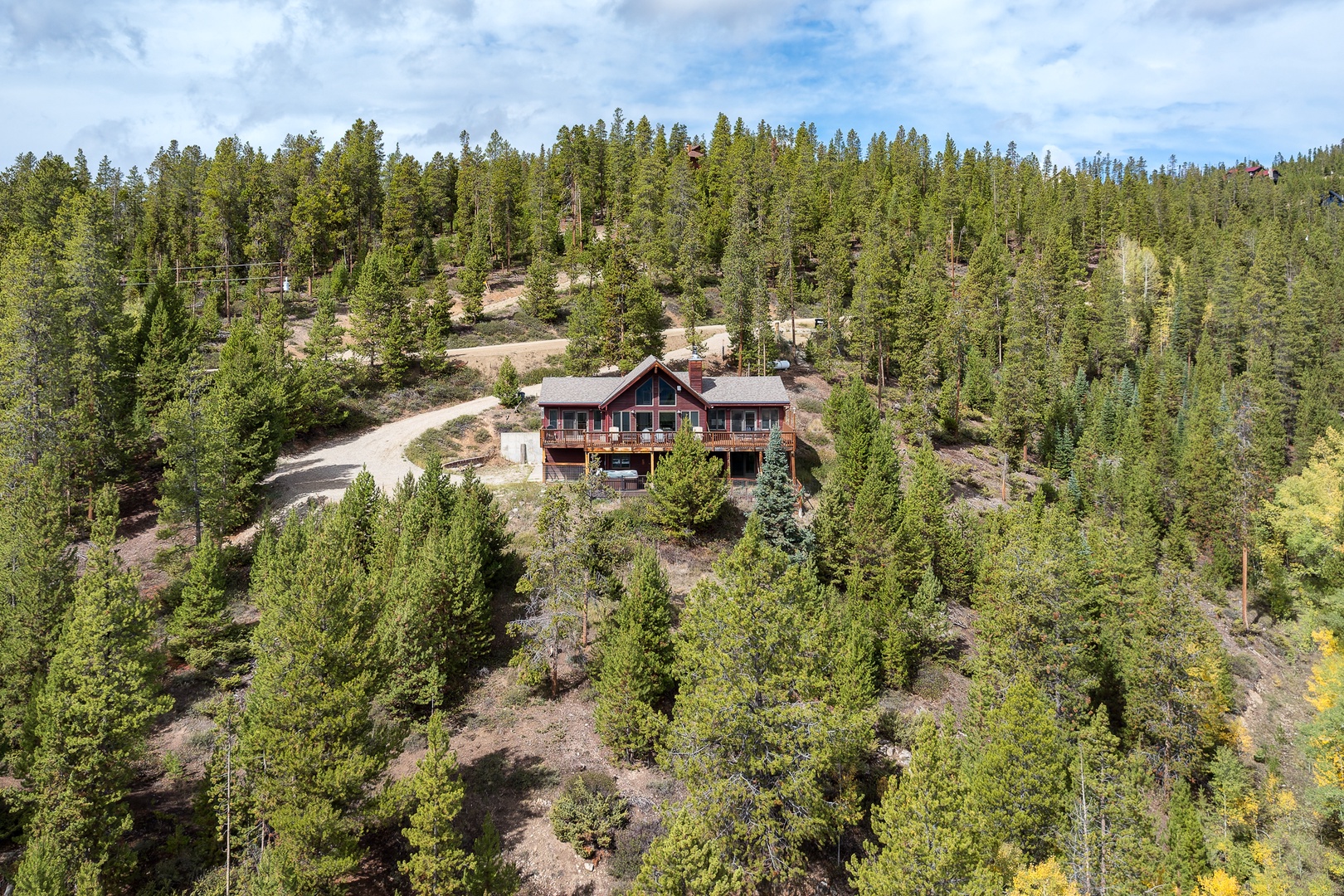 A secluded mountain lodge nestled among towering pines and natural forest terrain, offering a peaceful retreat surrounded by wilderness and scenic beauty.