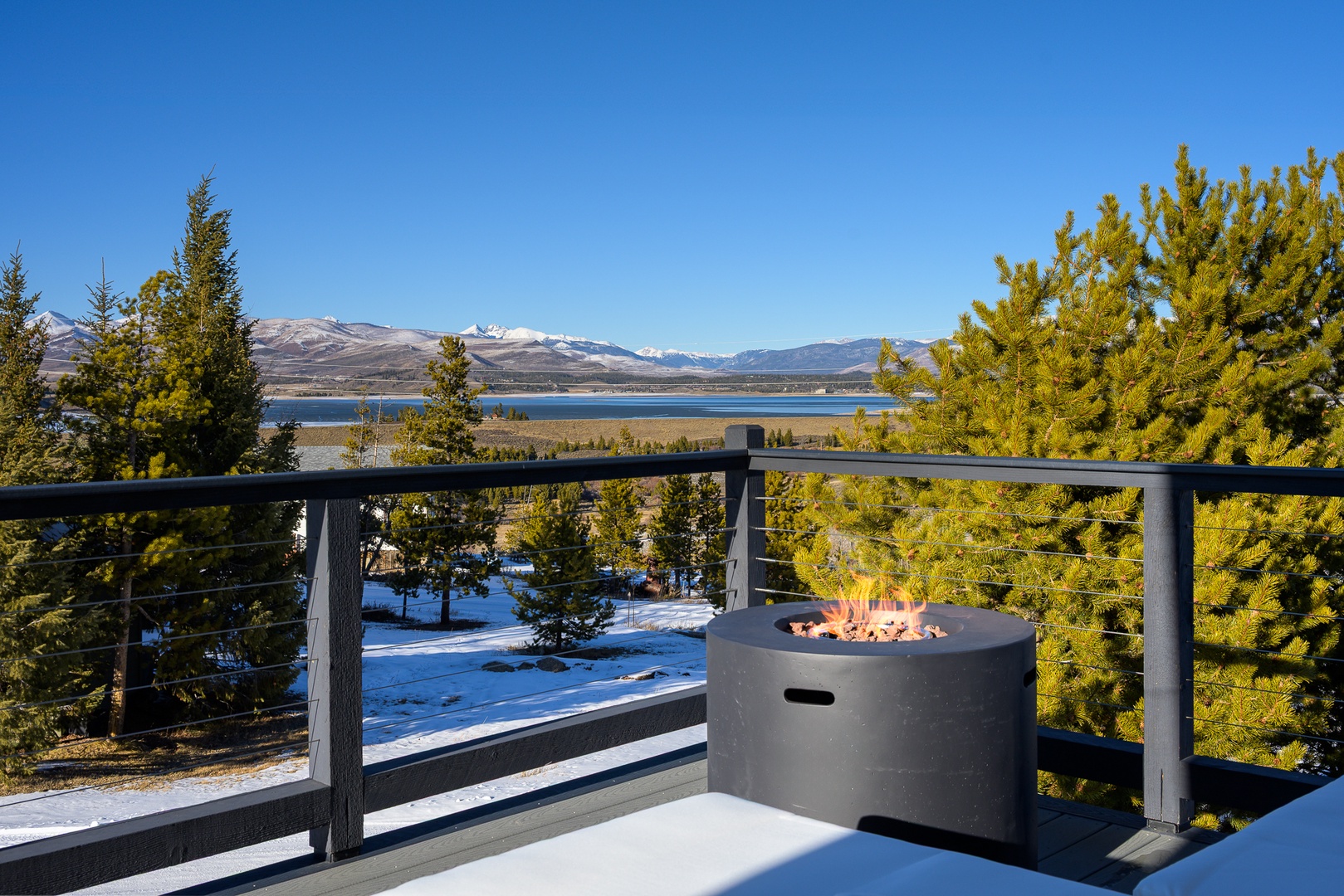 Stunning mountain and lake views stretch endlessly from this elevated deck, featuring a cozy fire pit for crisp winter evenings.