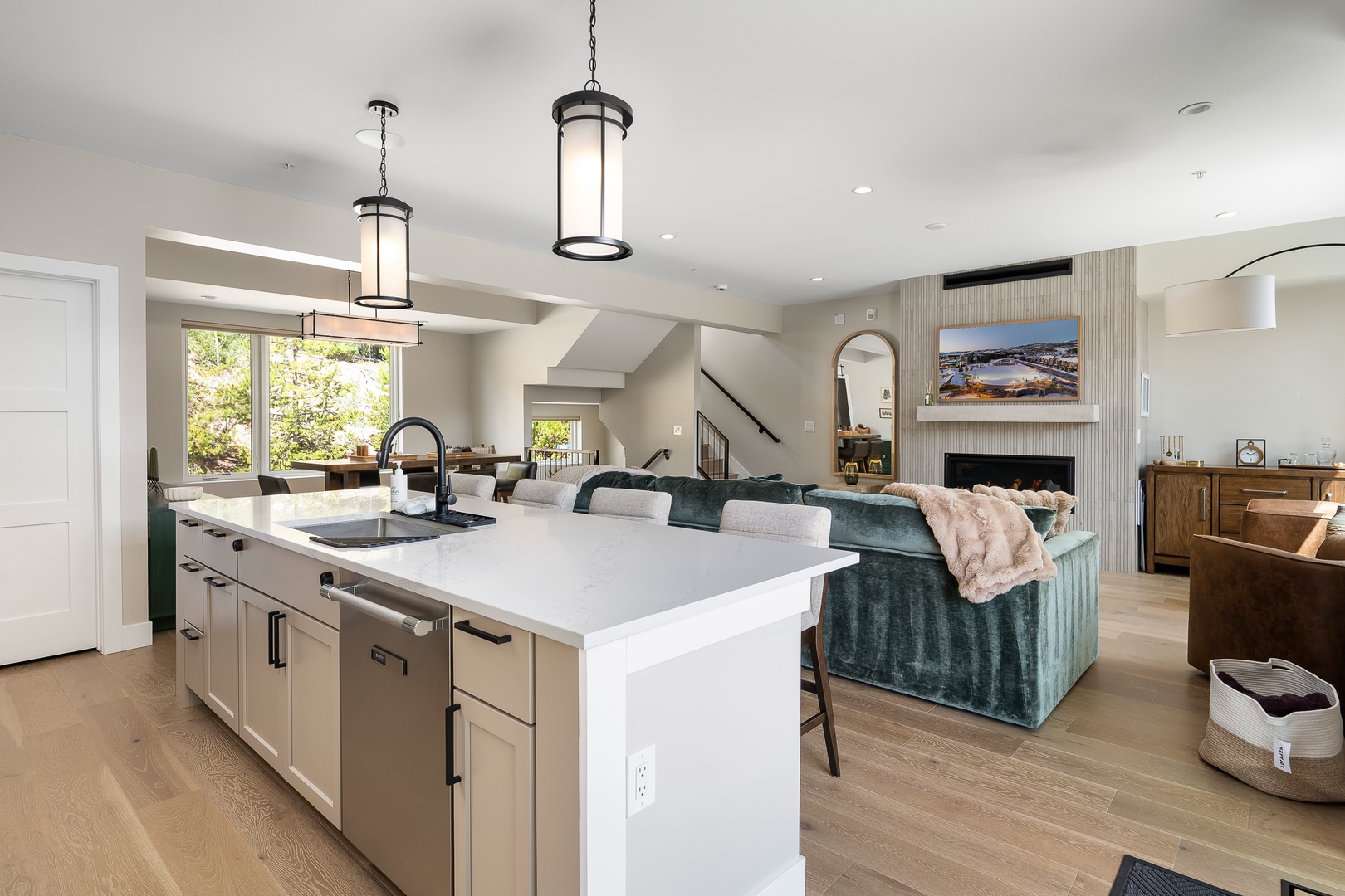 An open, inviting space where your mornings begin with natural light streaming through large windows. The sleek kitchen island flows seamlessly into the cozy living area, creating a perfect spot for gathering and relaxing together.