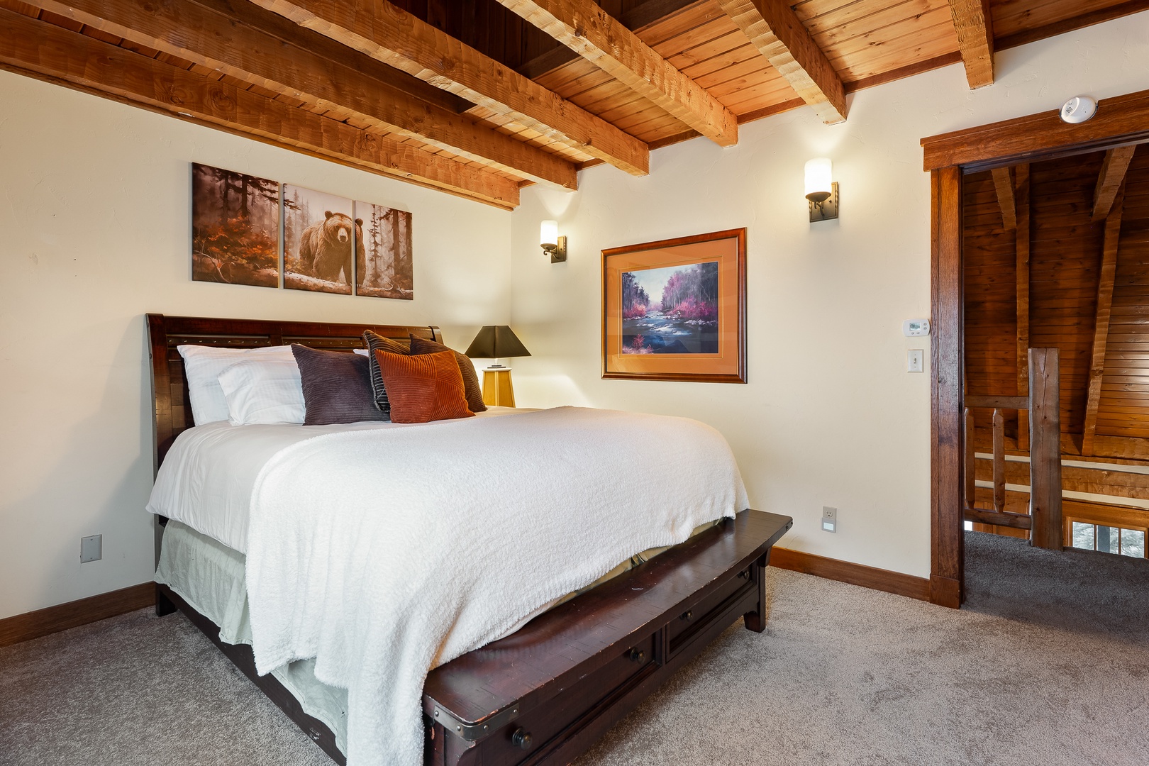 Rest peacefully under stunning exposed wooden beams in your cozy queen bedroom, where warm rustic charm meets modern comfort for the perfect mountain retreat.