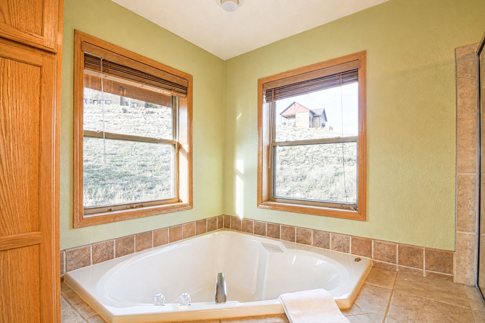 Soak away your cares in this bright corner tub with peaceful hillside views and natural light streaming through dual windows.