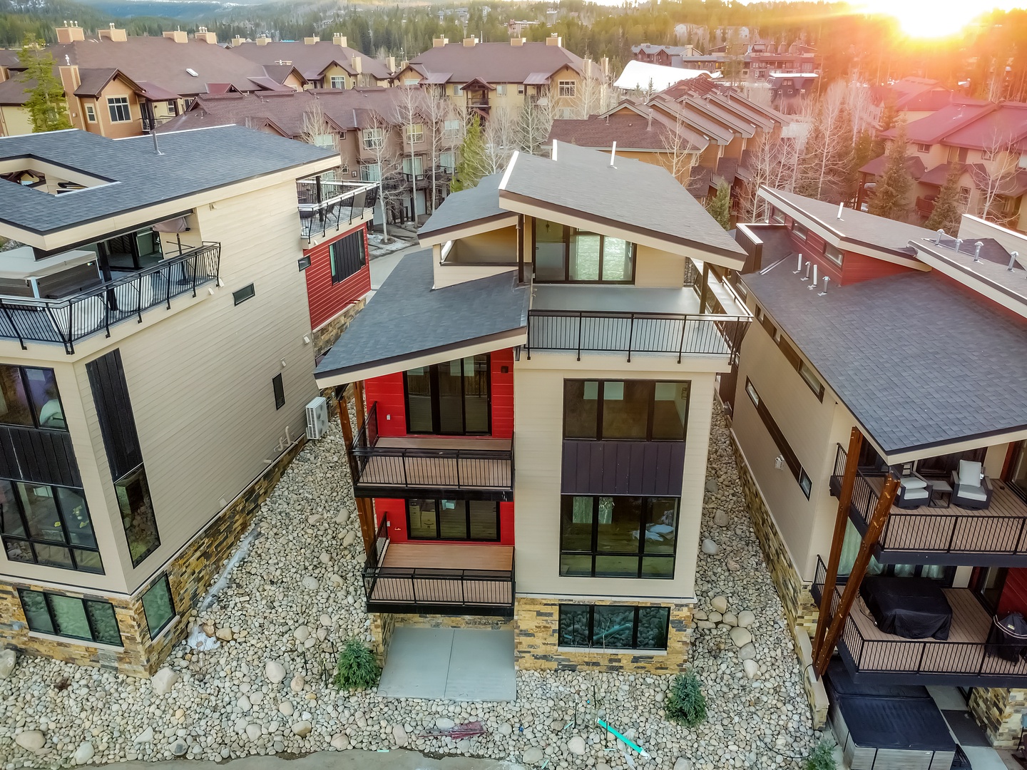 Modern mountain development featuring contemporary architecture with stone accents and multiple balcony levels amid residential neighborhood setting.