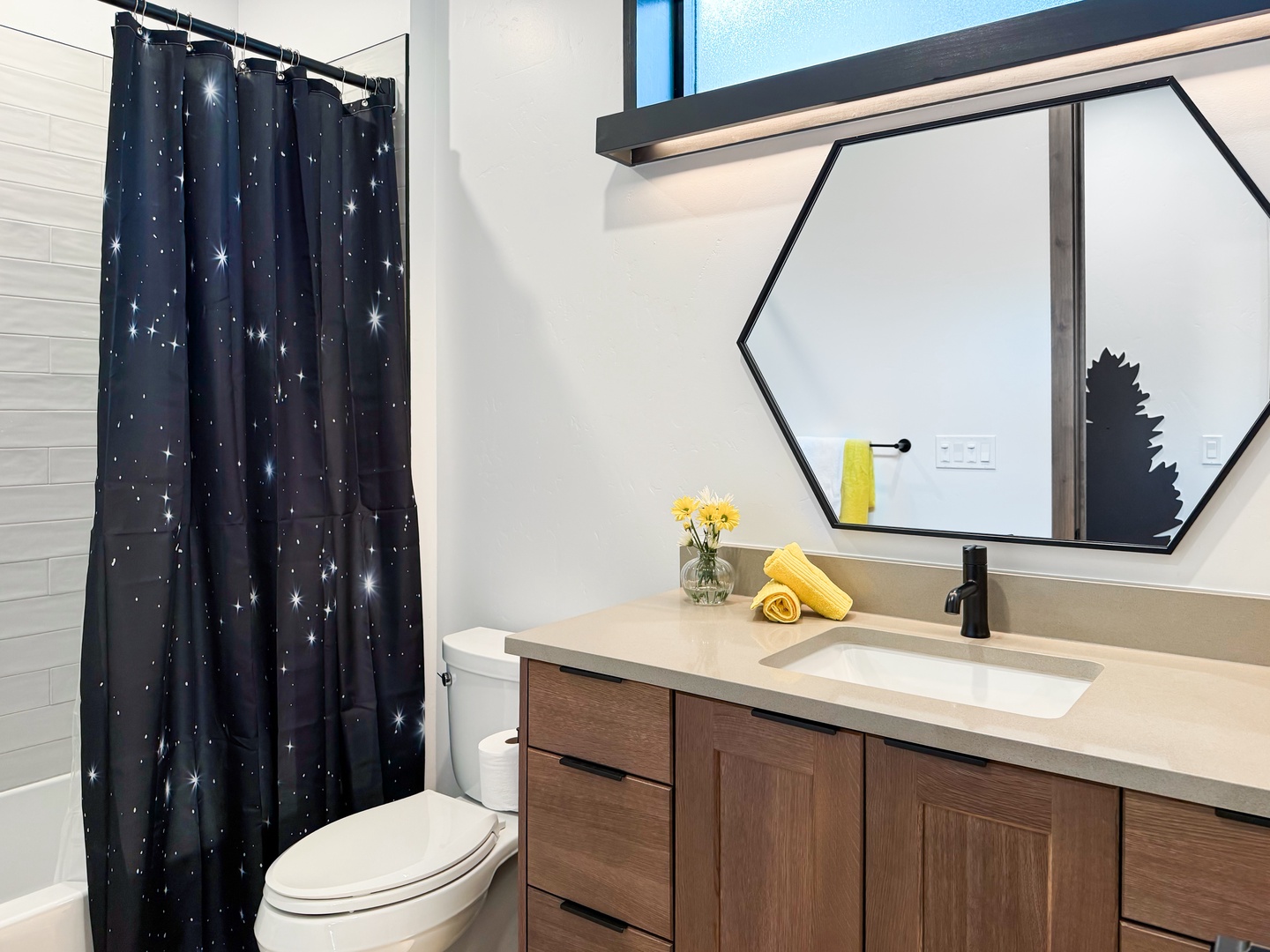 Freshen up in your modern bathroom, where warm wood tones meet crisp white finishes and playful touches like a star-lit curtain add charm to your daily routine.