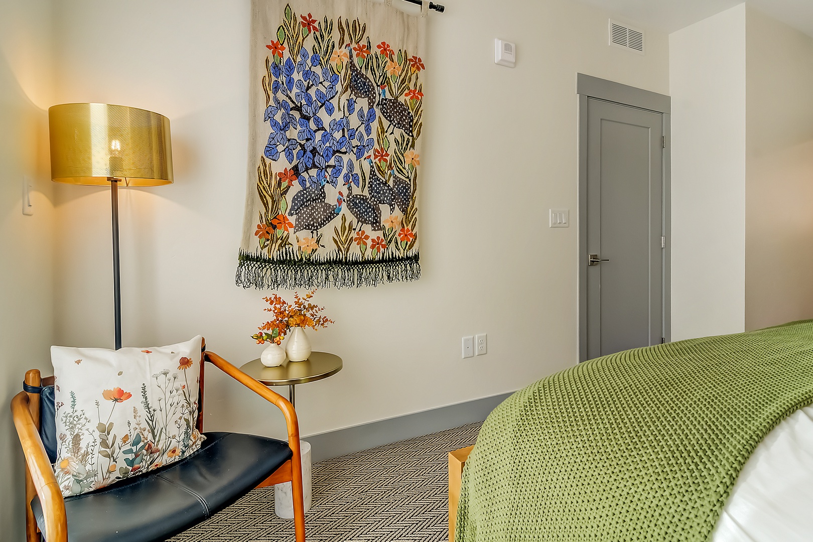 Unwind in your thoughtfully designed bedroom featuring vibrant botanical artwork and a cozy reading chair with your morning coffee.