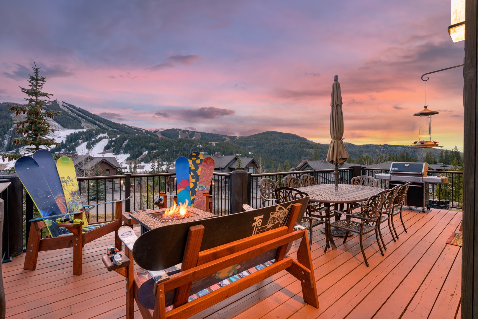 Enjoy cool summer Nights with Mountain-view deck with fire pit, dining area, and BBQ grill overlooking ski slopes at sunset.