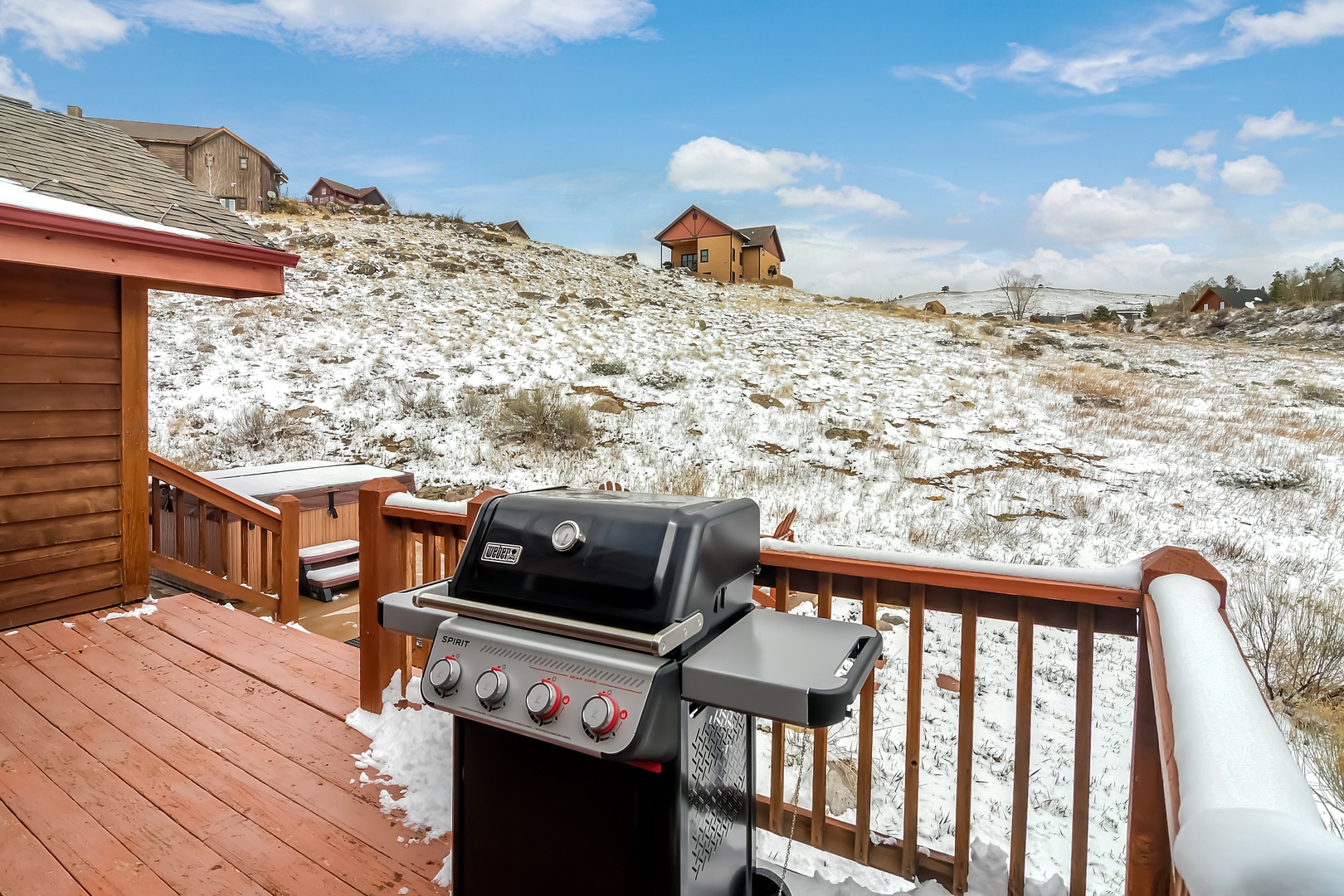 Winter deck with gas grill overlooking snowy landscape and scattered mountain homes.