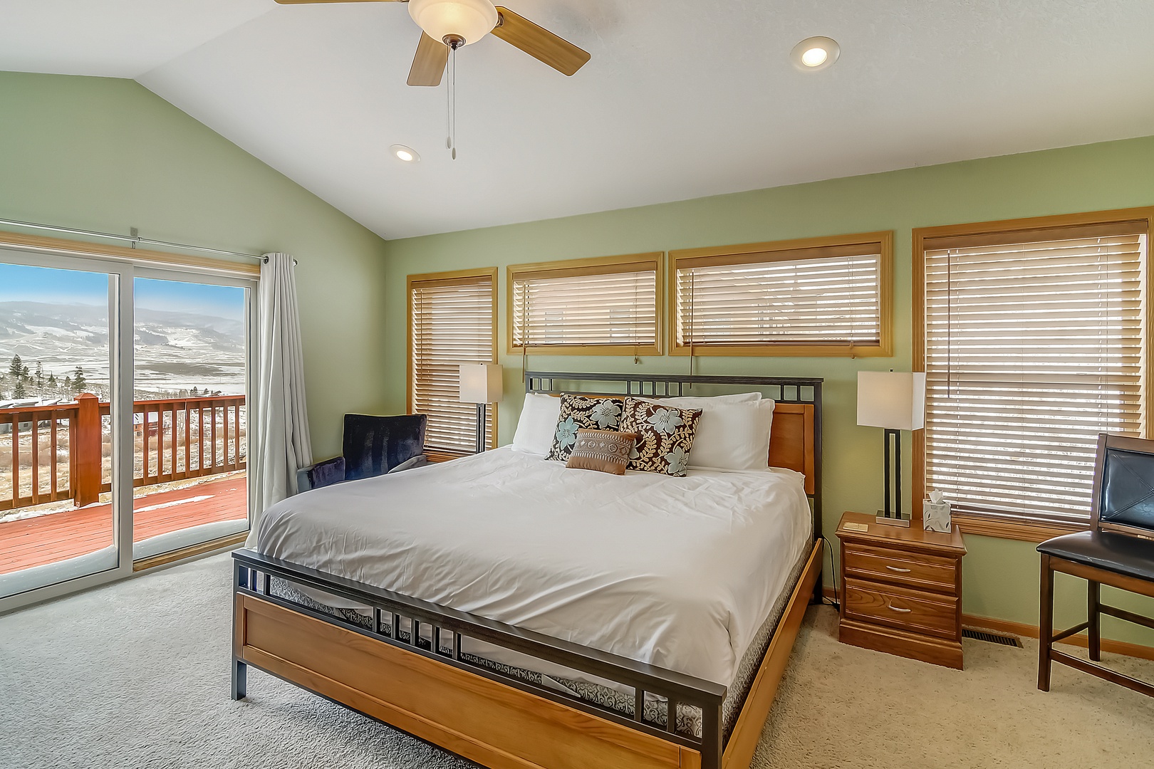 Wake up to stunning mountain views from your private balcony in this king bedroom with crisp linens and peaceful green tones.