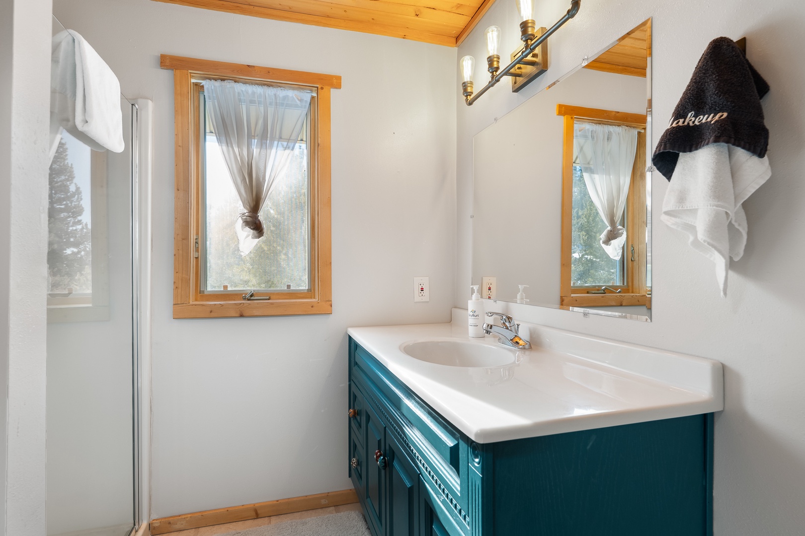 Refresh in your charming bathroom with rustic wood accents, natural light, and a beautiful teal vanity that adds character to your getaway.