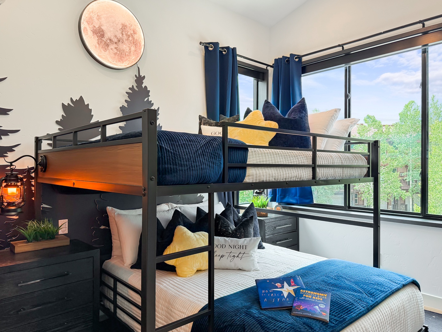Settle into your cozy bunk beds with whimsical forest wall art and soft mountain-inspired bedding. The large windows frame natural light and greenery, creating a peaceful retreat where restful nights await.