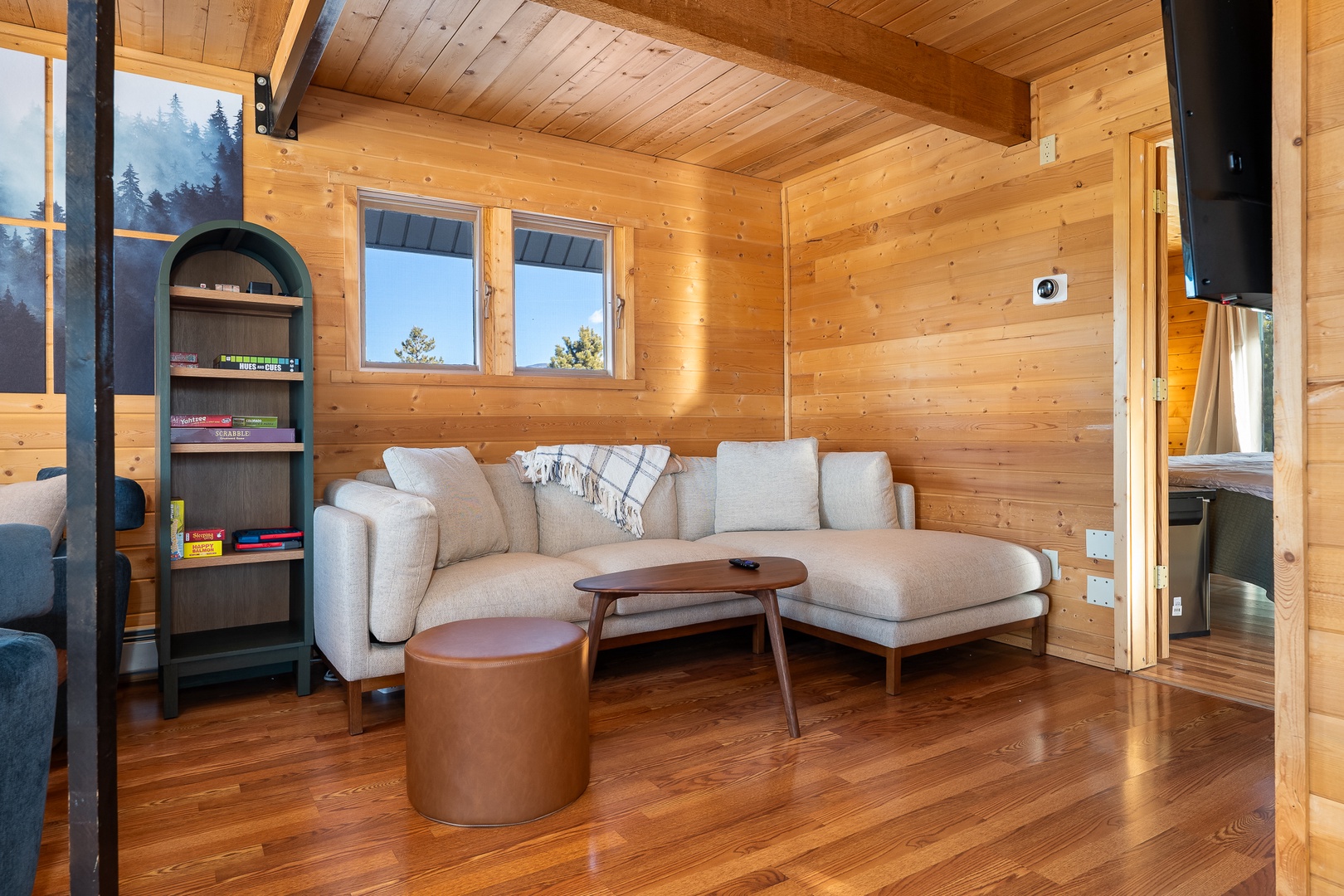 Unwind in your cozy living room with warm wood walls, plush sectional sofa, and mountain views through large windows.