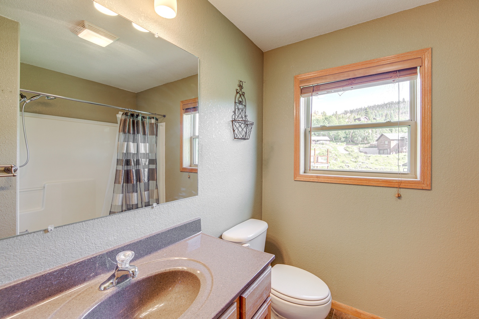 Freshen up in your private bathroom with modern vanity, shower, and peaceful hillside views through the charming window.