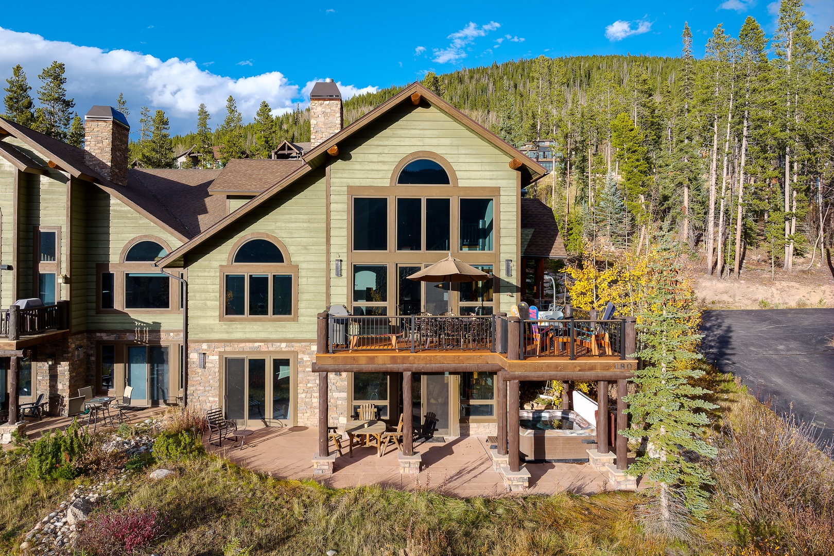 A stunning mountain retreat featuring rustic charm with stone and wood details, surrounded by pristine wilderness and towering peaks.