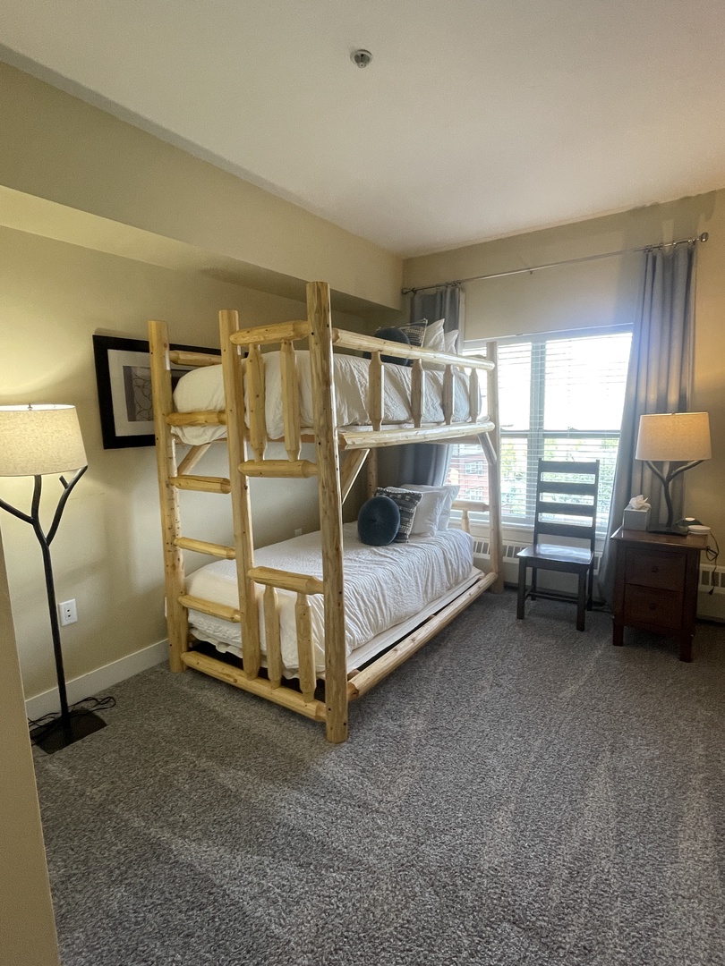 Your cozy bedroom features a wooden bed frame with crisp white linens, perfect for restful nights after exploring the city.
