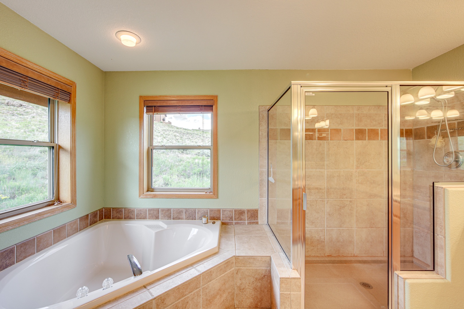 Unwind in your spacious bathroom with a deep soaking tub and separate glass shower, complete with peaceful nature views.
