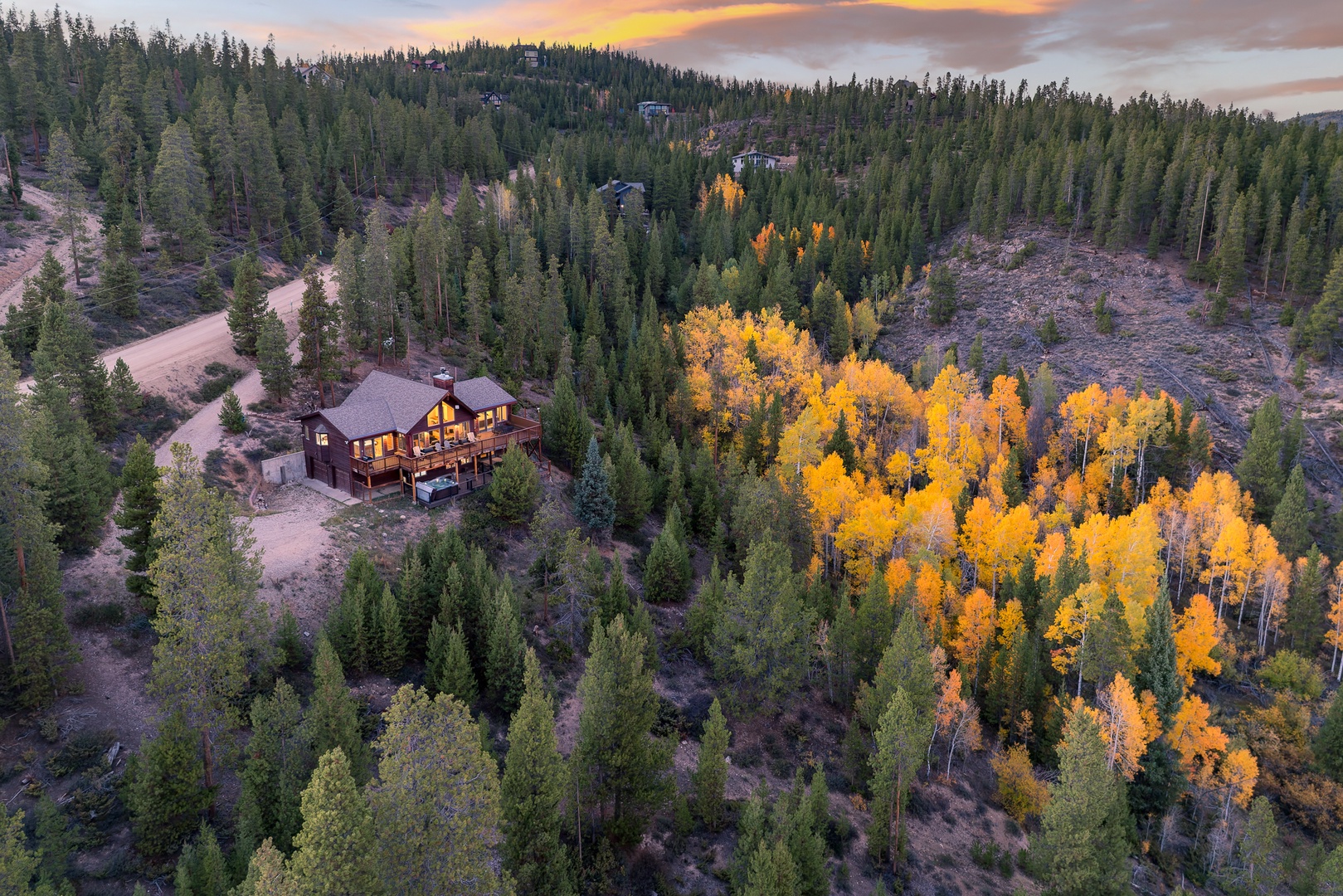 A stunning mountain retreat nestled among golden aspens and evergreens, surrounded by vibrant autumn colors and forest wilderness.