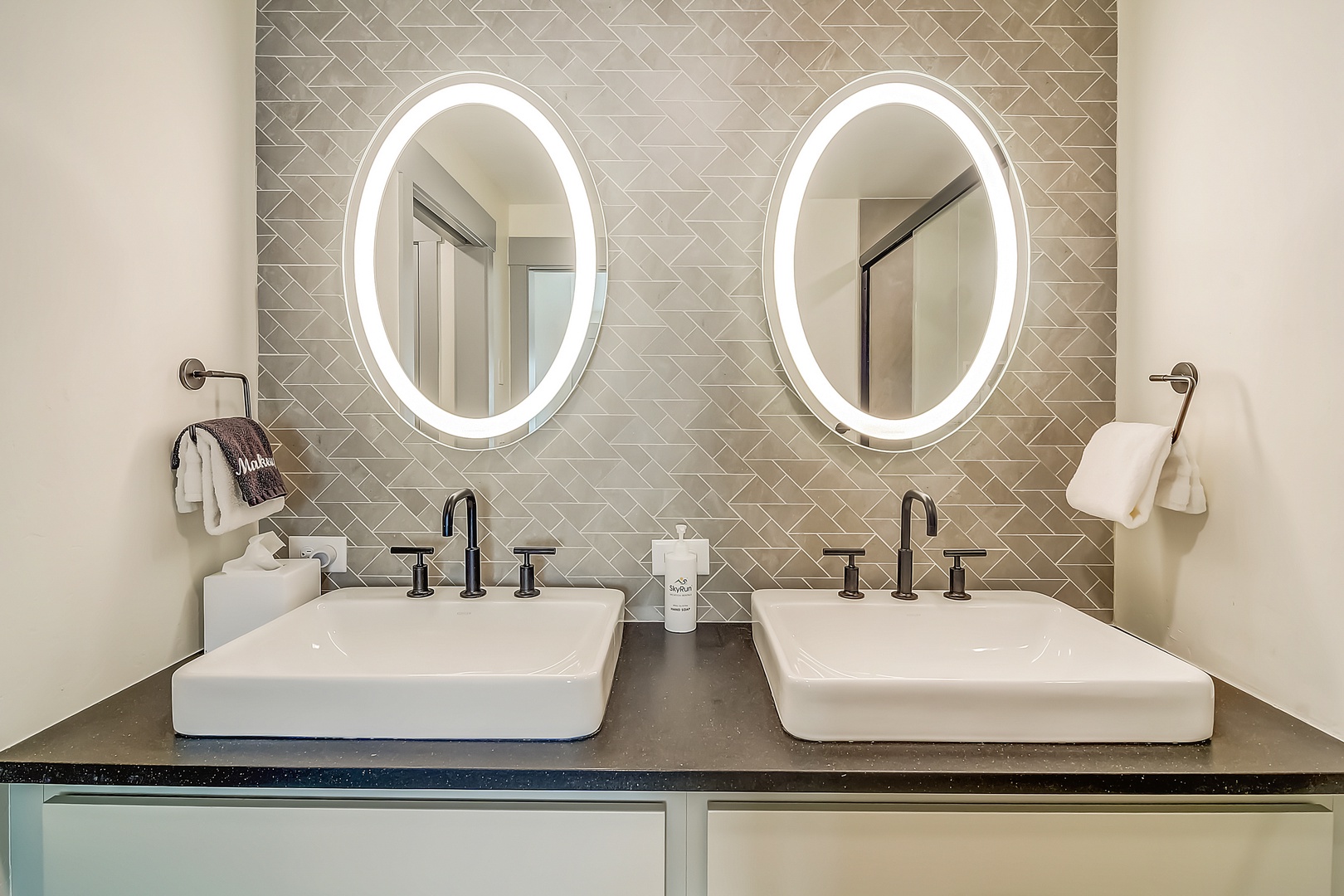 Refresh in your stylish dual-sink vanity with illuminated mirrors, designer tile backsplash, and modern fixtures.
