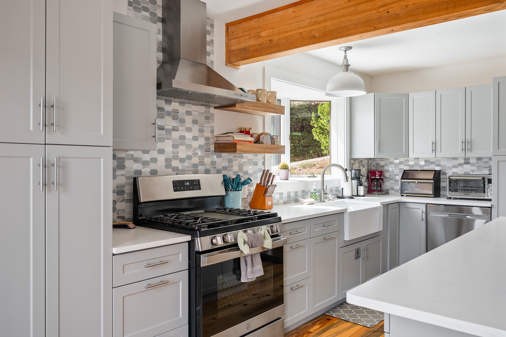 Picture yourself preparing your favorite meals in this bright, modern kitchen. The large farmhouse sink and gas range make cooking a pleasure, while the stylish hexagon backsplash and natural wood beams add warmth to the space.