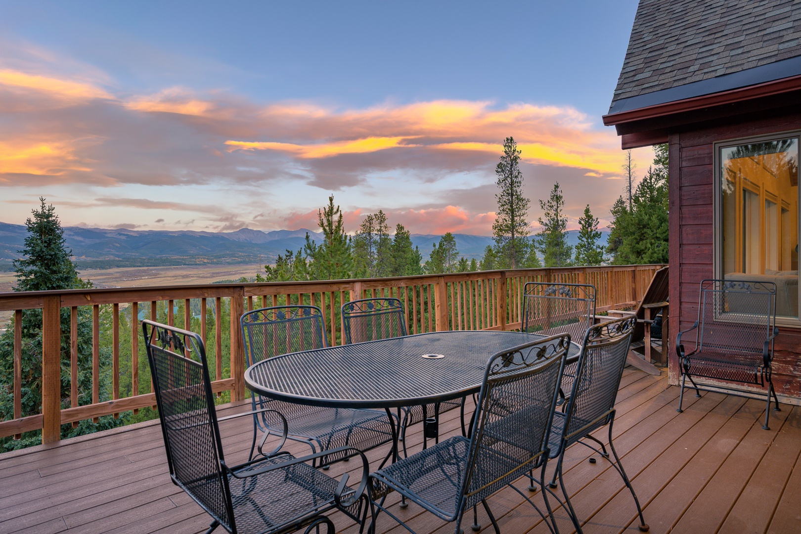 Stunning mountain views and vibrant sunset skies create the perfect backdrop for this spacious deck with dining for six, surrounded by evergreens and endless scenic beauty.