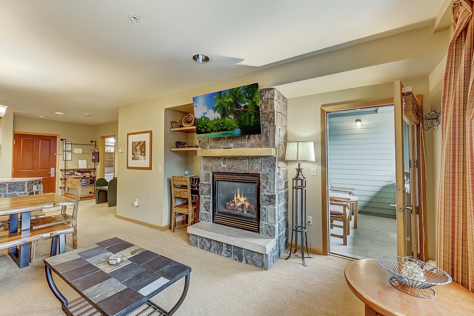 Unwind in your open-concept living space, where the stone fireplace creates a warm focal point and a patio looking down on the activity of the Village