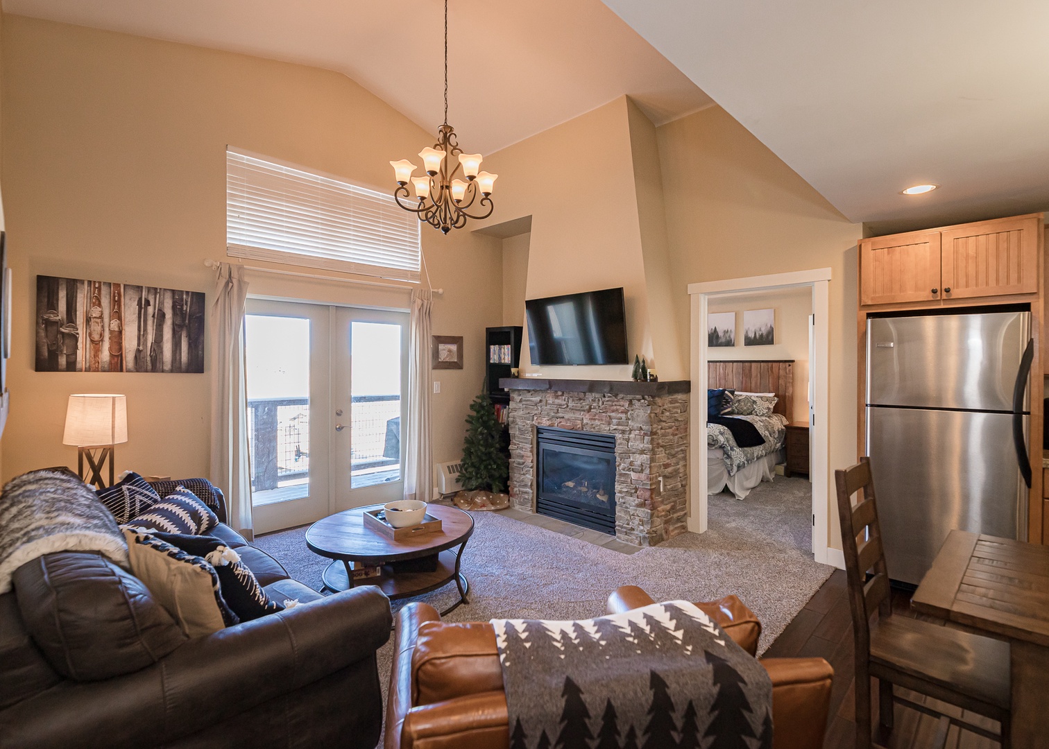Unwind in your cozy living space featuring a stone fireplace, vaulted ceilings, and mountain views through French doors to your private balcony.