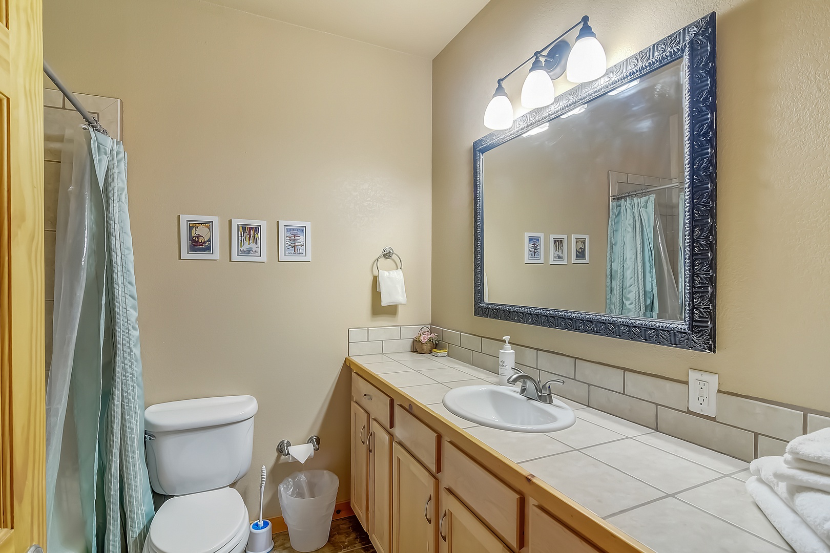 Freshen up in your private bathroom featuring a tiled vanity, decorative mirror, and shower-tub combo with thoughtful details throughout.