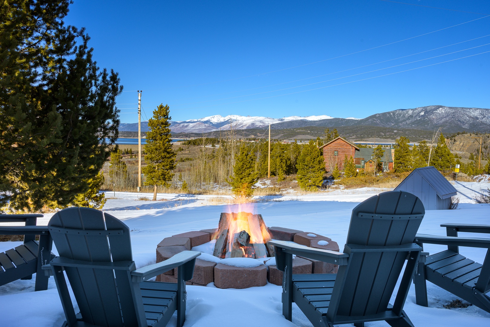 Cozy fire pit surrounded by Adirondack chairs creates the perfect winter gathering spot with stunning mountain views.