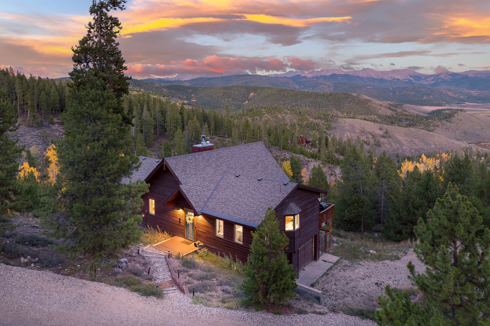 A secluded mountain retreat nestled among evergreens, where golden aspens and sweeping forest vistas meet dramatic sunset skies—your perfect escape into nature's quiet majesty.