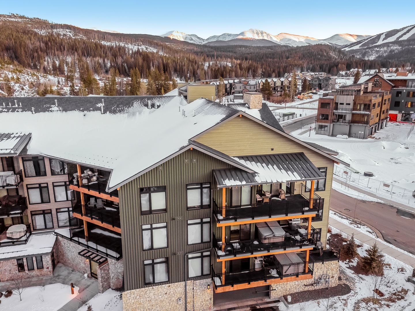Mountain ski village property surrounded by snow-covered peaks and forested slopes in winter resort town setting.