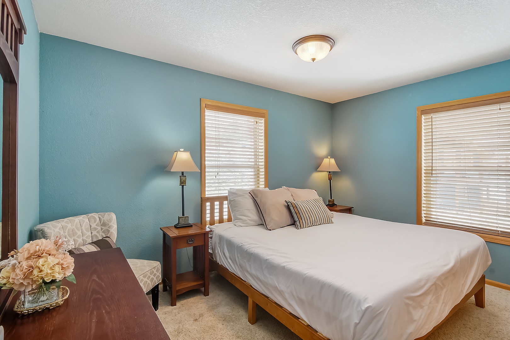 Drift off in this peaceful bedroom with soothing blue walls, crisp white linens, and warm wood accents creating your perfect retreat.
