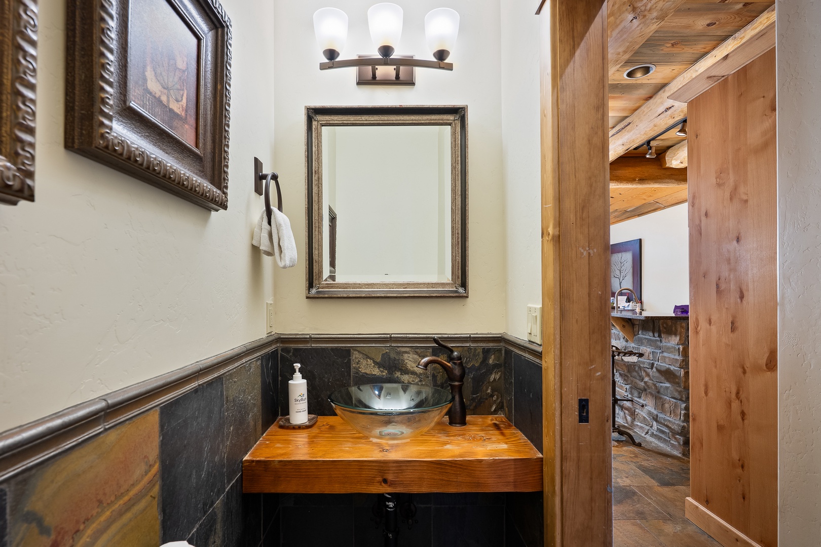 Refresh in your rustic powder room with elegant stone accents, warm wood vanity, and charming vessel sink.