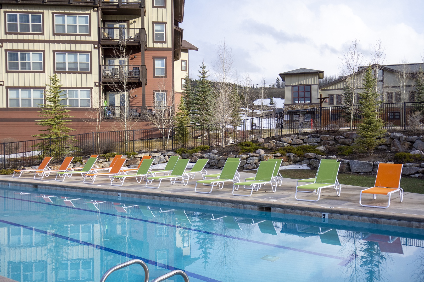 Outdoor pool surrounded by mountain views and landscaping, with colorful lounge chairs lining the deck—perfect for relaxing after a day of adventure in the surrounding area.