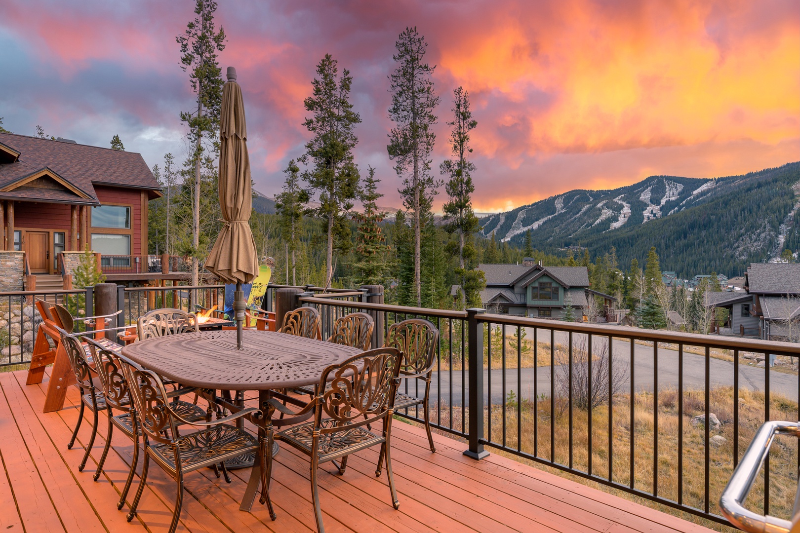 Mountain home deck offers stunning sunset views with spacious outdoor dining for eight guests amid Colorado's natural beauty.
