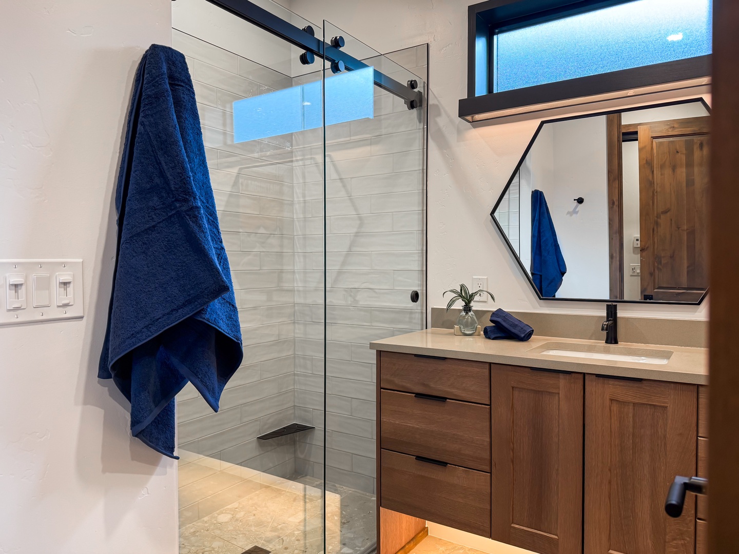 Refresh after your adventures in your modern bathroom, featuring a spacious glass-enclosed shower and warm wood accents that create a serene, spa-like atmosphere.