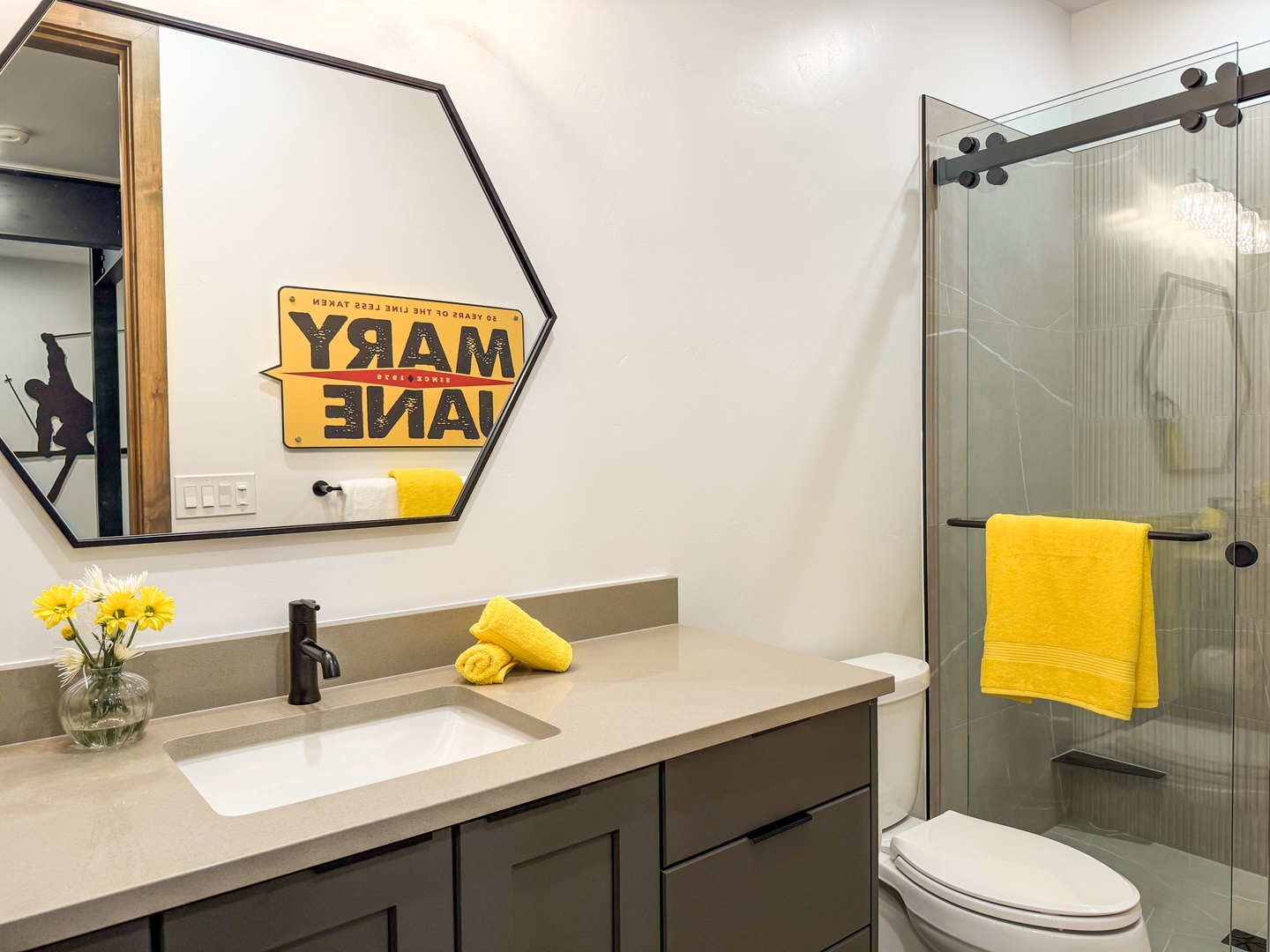 Your private bathroom features a sleek glass shower, modern vanity with fresh towels, and cheerful décor—a bright, clean space to freshen up after a day of adventure.